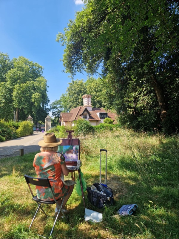 An artist sat outside on a summer's day creating a picture of a house