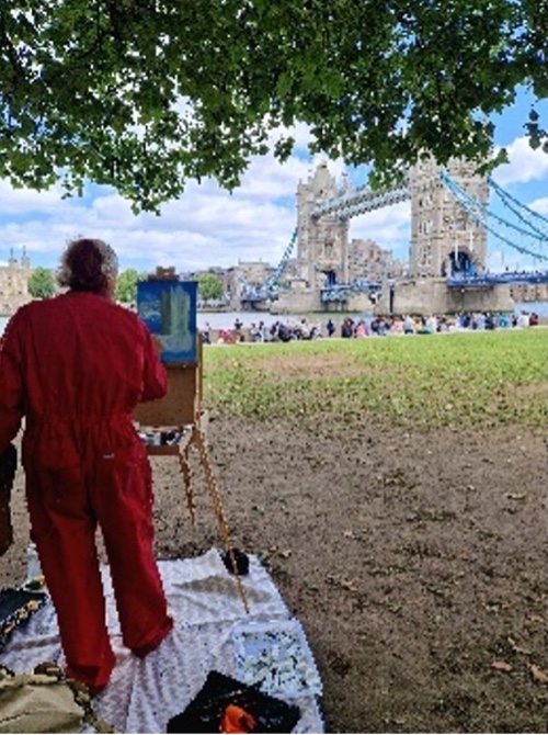 An artist outside observing and painting a picture of London's Tower Bridge.