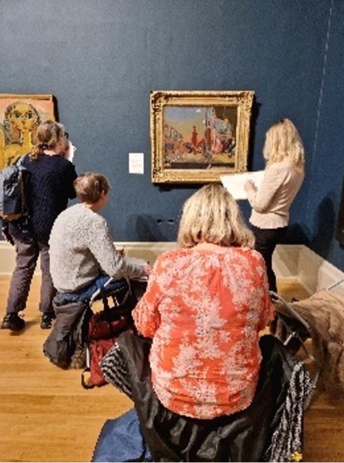 Group of artists observe and sketch a painting in a gallery.