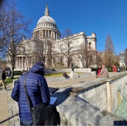 An artist outside observes and sketches St Paul's Cathedral in London.